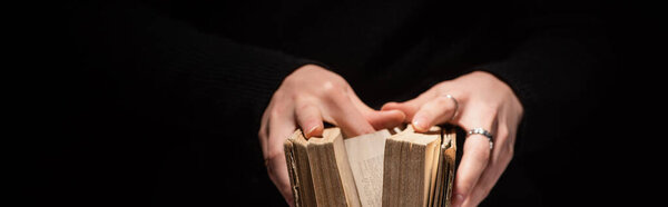cropped view of woman holding holy bible isolated on black, panoramic shot