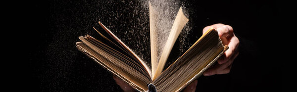 cropped view of woman holding holy bible with dust on black background, panoramic shot