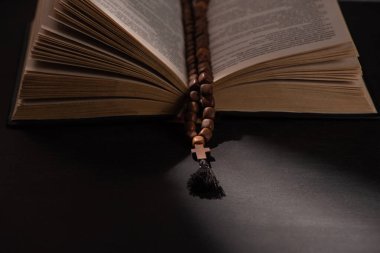 holy bible with rosary on black dark background with sunlight  clipart
