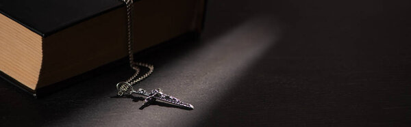 Священная Библия с крестом на черном темном фоне с горящими свечами, панорамный снимок
