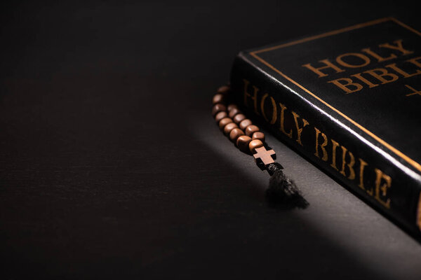 holy bible with rosary on black dark background