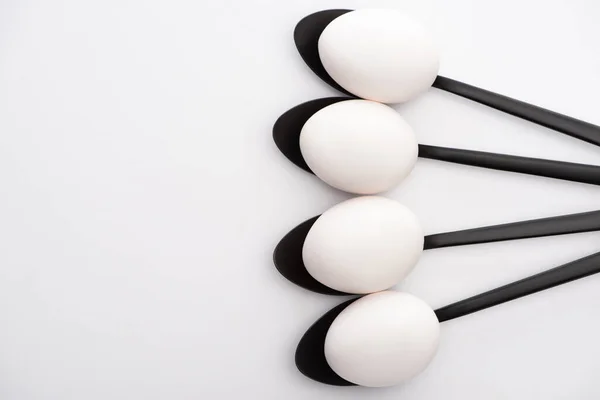 Beyaz Yüzeyde Siyah Kaşıklarda Tavuk Yumurtalarının Üst Görüntüsü — Stok fotoğraf