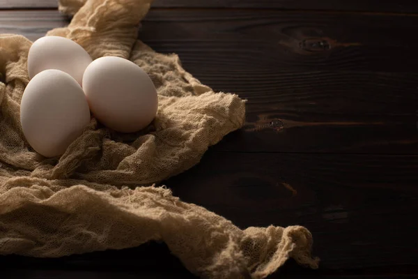 深色木制背景下褐色纱布上的白色鸡蛋 — 图库照片