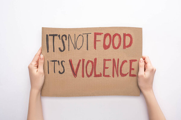 partial view of woman holding cardboard sign with its not food its violence inscription on white background