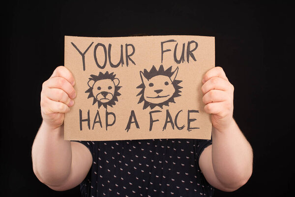 man with obscure face holding sign with your fur had a face inscription isolated on black