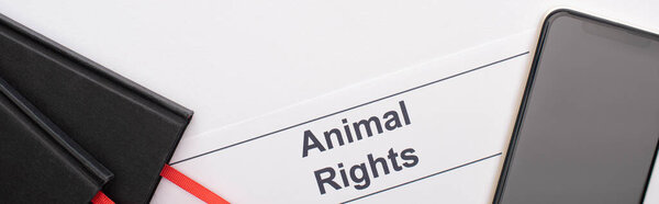 panoramic shot of animal rights inscription, black notebooks and smartphone on white background