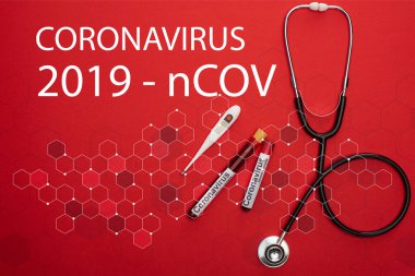 Stetoskop, termometre ve kan örnekleriyle test tüpleri ve kırmızı arkaplanda Coronavirus 2019-ncov harfleri.