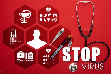 Stetoskop, termometre ve kan örnekleriyle test tüplerinin üst görüntüsü ve kırmızı arkaplanda virüsü durdurma