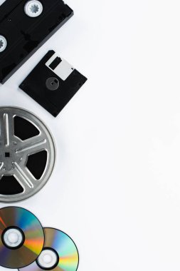 VHS kasetlerinin üst görünümü, CD diskler, disketler ve beyaz arkaplanda film makarası 