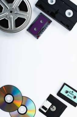 top view of CD discs, cassettes, VHS cassette, diskette and film reel on white background clipart