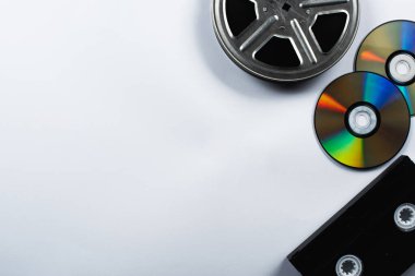 top view of CD discs, VHS cassette and film reel on white background clipart