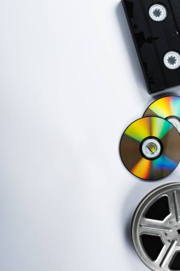 CD disklerin üst görünümü, VHS kaset ve beyaz arkaplanda film makarası
