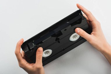 partial view of man holding old VHS cassette on white background clipart