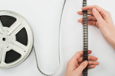 Beyaz arka planda film şeridi tutan adamın kısmi görüntüsü