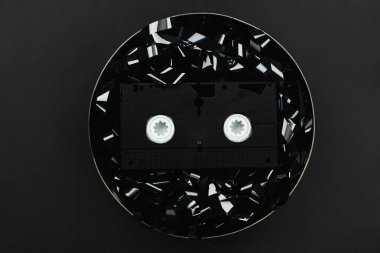 Siyah film şeridi üzerindeki VHS kasetinin en üst görüntüsü siyah üzerine izole edilmiş teneke kutuda