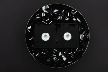 top view of VHS cassette on black film strip in tin case isolated on black clipart