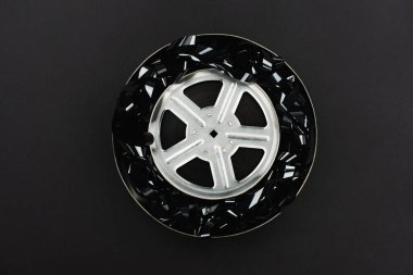 Siyah film şeridinin üst görüntüsü ve siyah üzerine izole edilmiş paslı teneke kutuda film makarası
