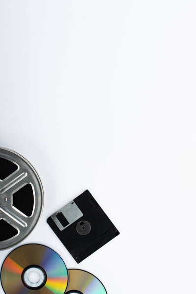 top view of CD discs, diskette and film reel on white background