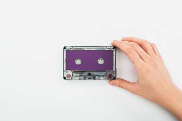 partial view of man holding purple recording cassette on white background