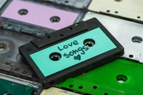 stock image high angle view of turquoise cassette with love songs inscription on colorful cassettes