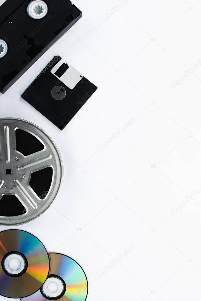 top view of VHS cassette, CD discs, diskette and film reel on white background 