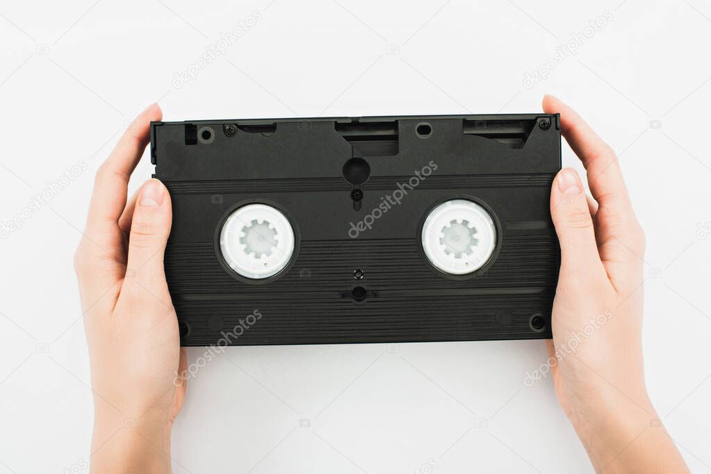 partial view of man holding black VHS cassette on white background