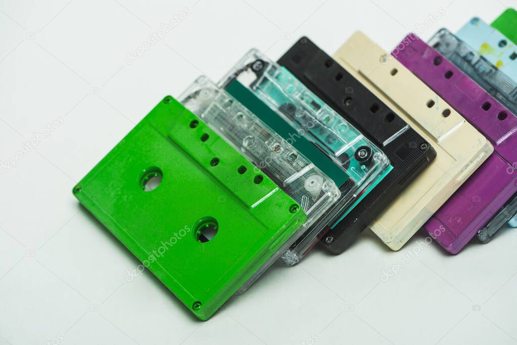 green, turquoise, purple and black retro cassettes on white background