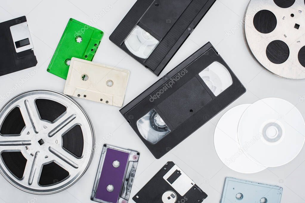 flat lay of VHS cassettes, diskettes, CD discs, film reels and colorful cassettes on white background