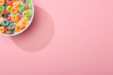 Pembe arka planda sütü olan parlak renkli kahvaltı gevreğinin üst görüntüsü