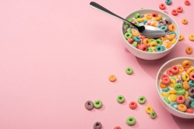 bright colorful breakfast cereal with milk in bowls with spoon on pink background clipart