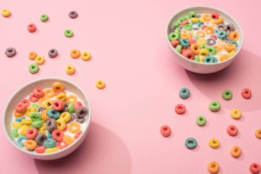 bright colorful breakfast cereal with milk in bowls on pink background clipart