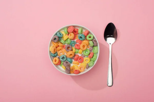 粉红背景的汤匙附近碗里色彩艳丽的早餐麦片的顶部视图 — 图库照片