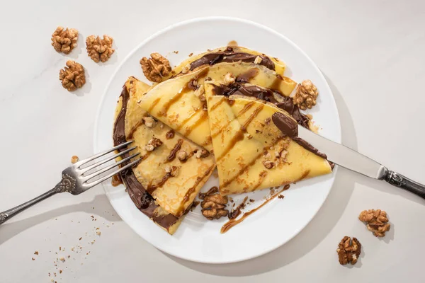 Bovenaanzicht Van Lekkere Crêpes Met Chocoladepasta Walnoten Bord Met Bestek — Stockfoto