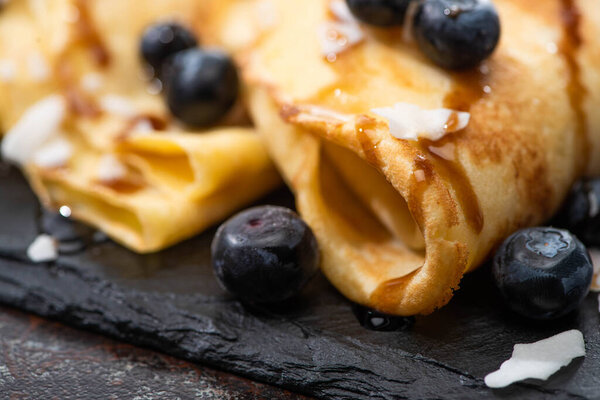 близкий обзор вкусных блинов с черникой, мятой и кокосовыми хлопьями, подаваемых на борту на текстурированном фоне
