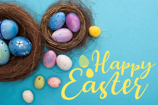 Horní Pohled Barevné Velikonoční Vajíčka Hnízdech Modrém Pozadí Šťastnou Velikonoční — Stock fotografie