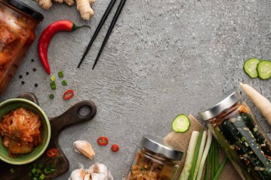 Kavanozlarda lezzetli kimchi ve yemek çubuklarının yanında kase, yeşil soğan, zencefil, sarımsak ve kırmızı biber.