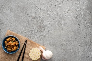 Lezzetli kimchi, yemek çubukları ve beton yüzeyde çuval bezi üzerine sarımsak.