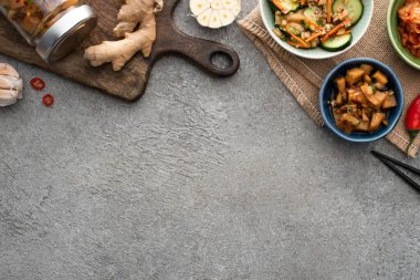 Tabaklardaki lezzetli kimchi ve kesme tahtasının yanındaki kavanoz, yemek çubukları, sarımsak ve zencefil.