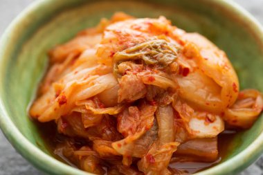 close up of tasty cabbage kimchi in green bowl clipart