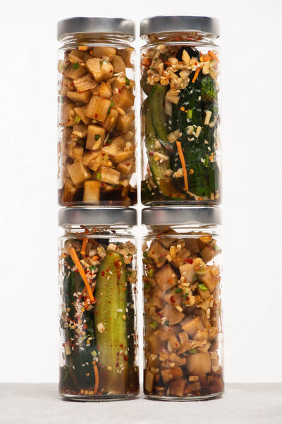огурец и дайкон редис кимчи в стеклянных банках, изолированных на белом
