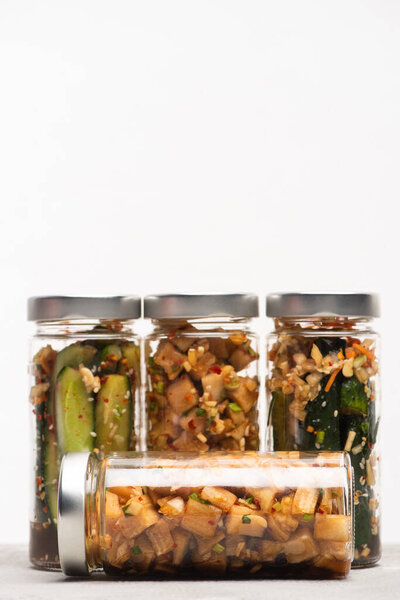 tasty daikon radish and cucumber kimchi in jars isolated on white
