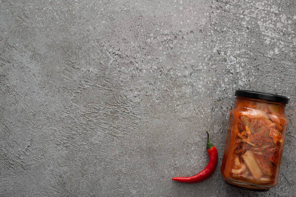 top view of red chili pepper and kimchi jar on grey concrete background