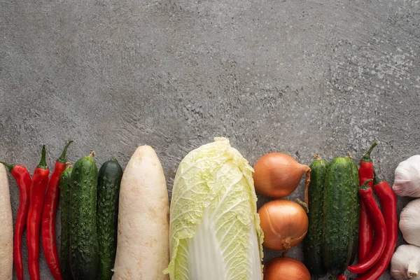 Top view of chili peppers, cucumbers, daikon radish, chinese cabbage, onions and garlic on grey concrete background — Stock Image Top View Chili Peppers Cucumbers Daikon Radish Chinese Cabbage Onions Royalty Free Stock Photos