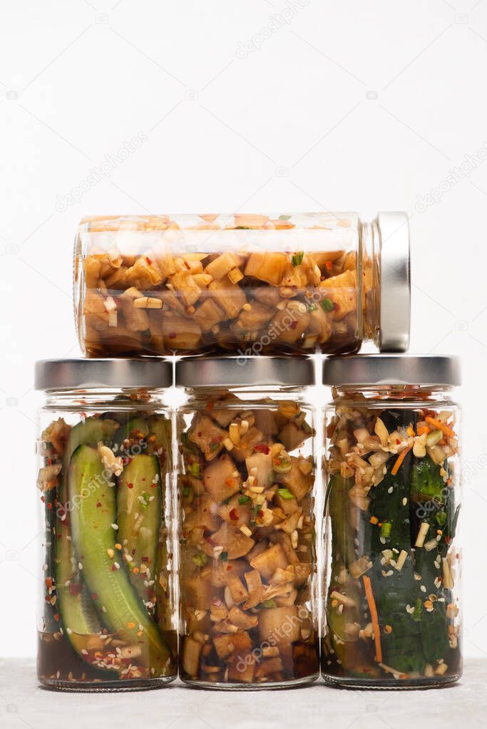 delicious daikon radish and cucumber kimchi in jars isolated on white