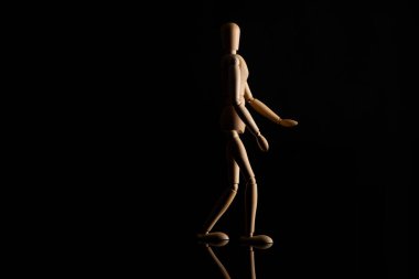 Wooden doll imitating walking on black background clipart