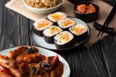 Tahta yüzeyde çubukların yanında somon balığı olan seçici bir gimbap. 