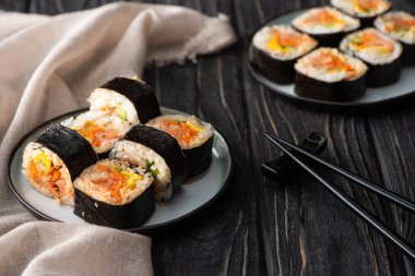 Sebzeli lezzetli gimbap ve somon yemek çubuklarının yanında, ahşap yüzeyde. 