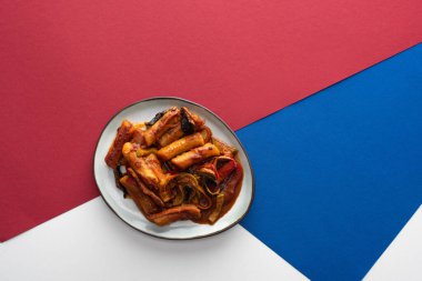 top view of tasty stir-fried korean tteokbokki on white blue and crimson  clipart