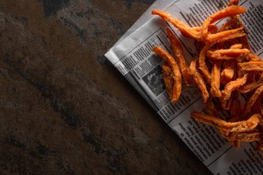 Gazete yakınlarındaki mermer yüzeyde lezzetli patates kızartması manzarası.  