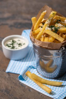 Kovanın seçici odağı tuzlu patates kızartması ve mermer yüzeyde kremalı sarımsak sosu. 